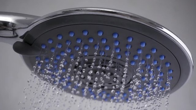 Shower head in bathroom with water drops flowing. Slow motion
