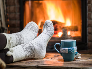 Warming and relaxing near fireplace with a cup of hot drink.