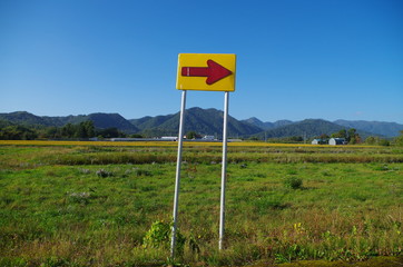 草地と矢印の注意看板