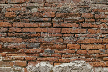 Old red brick wall cover with white cement which is peeling off.