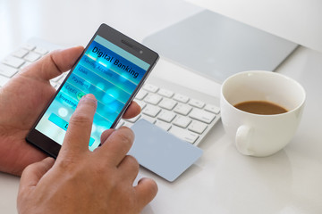 Mobil payment or digital banking concept. Hand holding smart phone and touching Digital banking application on screen with blank card, cup of coffee on the working desk.