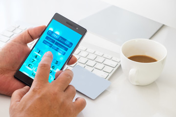 Mobil payment or digital banking concept. Hand holding smart phone and touching Digital banking application on screen with blank card, cup of coffee on the working desk.