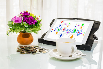 P2P lending concept. Cup of coffee, money coins, flower pot and digital tablet with Peer to Peer icons and message on screen.