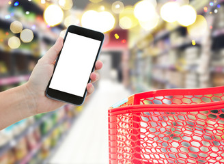 someones hand holding mobile smart phone with empty screen on supermarket blur background with red...