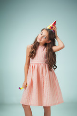 The cute cheerful little girl with festive cap on gray background