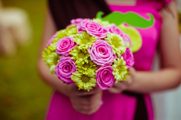 Woman in pink dress holds yellow and pink flowers