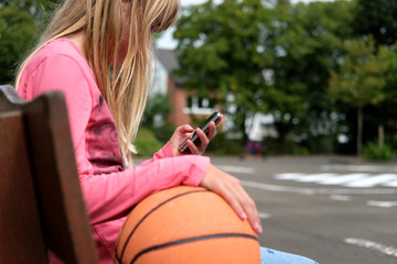 Junges Mädchen nutzt alleine ihr Smartphone anstatt mit anderen zu spielen - obrazy, fototapety, plakaty