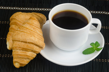 fresh cup of hot black coffee with croissants