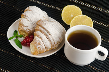 fresh cup of hot black coffee with croissants and lemon