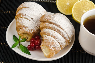 fresh cup of hot black coffee with croissants and lemon