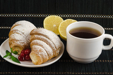 fresh cup of hot black coffee with croissants and lemon