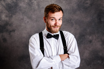  bearded man in white shirt and bow tie in front of gray backgro