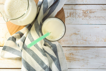 fresh milk in glass jug and glass on wooden background