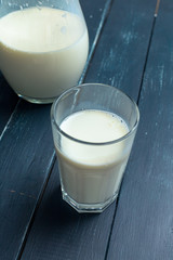 fresh milk in glass jug and glass on wooden background