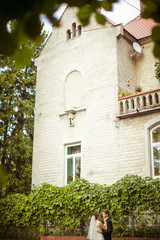 White walls of an old house raise over the hugging wedding coupl