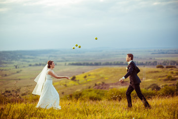Apples fly over the wedding couple playing on the field