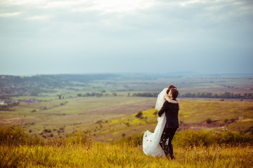 Groom raises a beautiful bride up in the air while standing on t