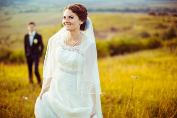 Fototapeta na wymiar Radiant bride smiles while standing on the yellow field