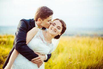 Groom hugs bride tightly from behind and kisses her head