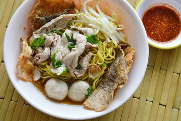 Chinese egg noodle with pork ball topping crispy fish skin in soup and chili sauce