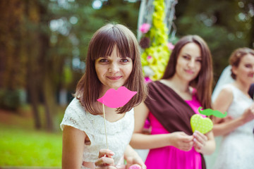 Pretty bridesmaid raises a stick with pink paper lips