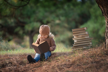 маленькая девочка читает книгу в парке