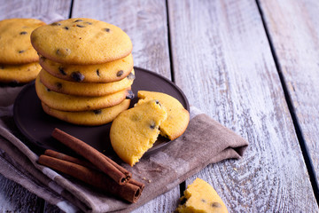 Homemade Pumpkin Spice Cookies with chocolate chips or drops on Halloween,cinnamon sticks. Wooden background. Copy space