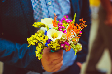Man in blue suit holds bright bouquet