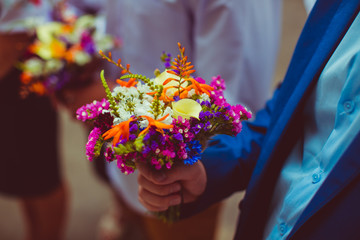 Colorful little bouquet held by a man in blue suit