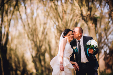 Wedding couple background dry tree and coniferous trees. Kissing man and woman. Middle age newlyweds.