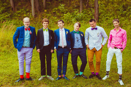 Groom's band surround him while posing in the wood