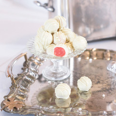 a bunch of white-and-red candies on a glass stand reflecting in a shabby silver tray