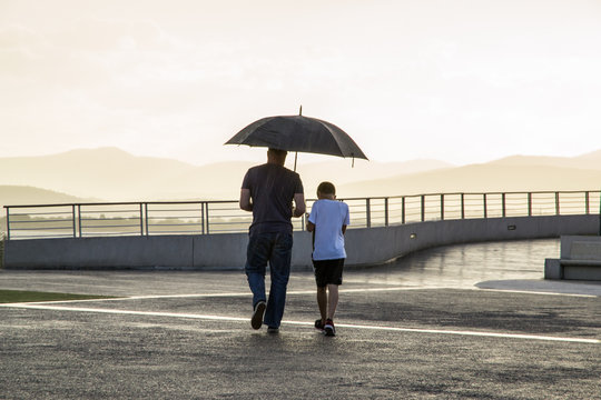 Padre e figlio sotto la pioggia al tramonto