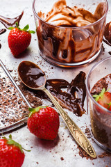 Chocolate mousse with strawberries in glass on rustic table