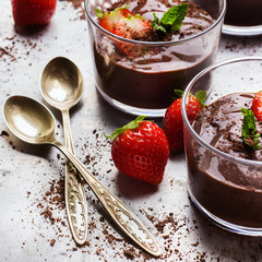 Chocolate mousse with strawberries in glass on rustic table