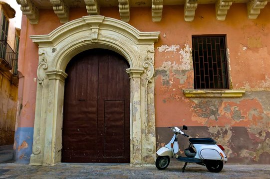 motorbike against backdrop of classic architecture and peeling paint in Gallipoli, Italy