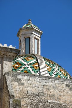 Ostuni Italy Romanesque cathedral tiled dome rooftop beneath blue sky
