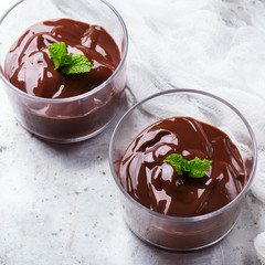 Chocolate mousse with mint in glass on rustic table