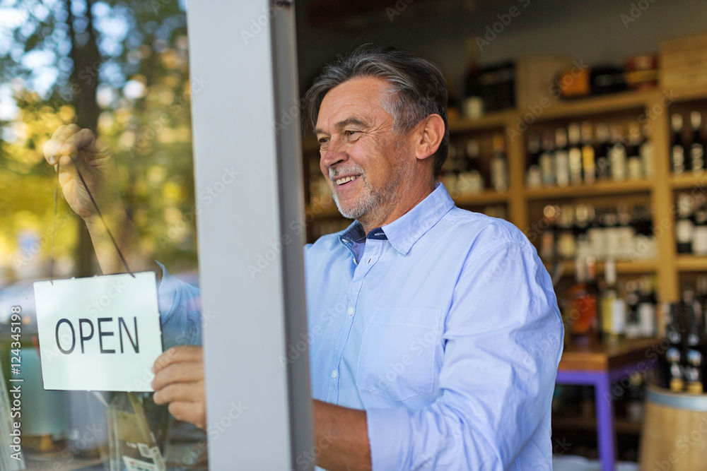 Wall mural Wine shop owner holding open sign
