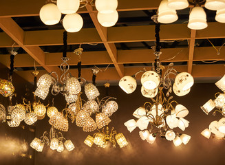 A lot of beautiful chandeliers with glass shades hanging from the ceiling in the sales area.