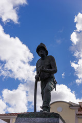 Firefighter statue with blue sky and clouds in the background