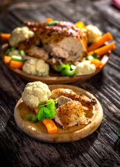 Whole roasted chicken with vegetables on wooden background