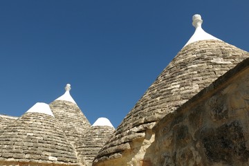 Fototapeta na wymiar Trulli, the plural of trullo, in Apulia, Italy. These unusual stone structures have conical rooftops and are specific to the Itria Valley. 