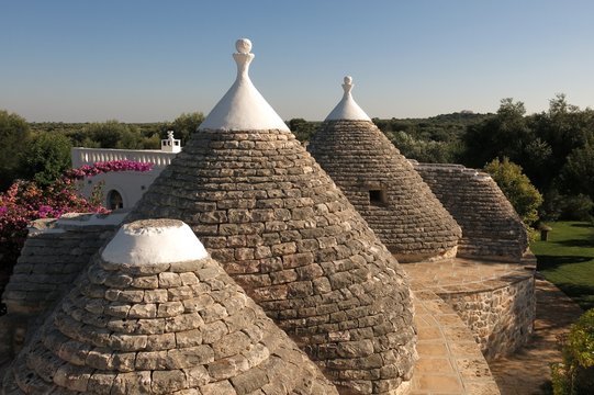 Trulli, the plural of trullo, in Apulia, Italy. These unusual stone structures have conical rooftops and are specific to the Itria Valley. 
