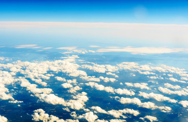 Fluffy white clouds and blue sky seen from airplane.