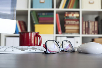 Computer and glasses with blur library background