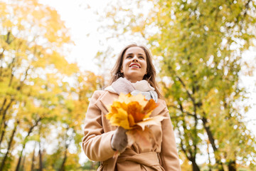 Naklejka na ściany i meble beautiful woman with maple leaves in autumn park