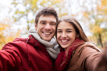 Fototapeta premium happy young couple taking selfie in autumn park