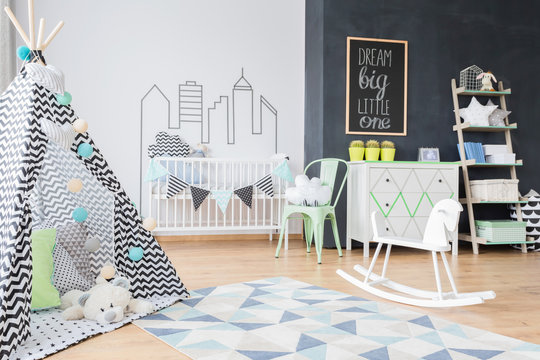 Shot of a stylish child's room interior with a black and white tent and a wooden rocking horse