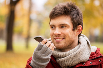 Fototapeta premium man recording voice on smartphone at autumn park